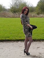 Redhead girl wearing leopard dress, grey pantyhose and high heels poses outdoors