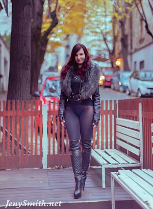 Jeny poses on a city street wearing just a stylish jacket, black seamless pantyhose and tall boots, her feminine curves and private areas fully on display